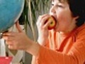 Young boy eating apple and looking at the globe | BahVideo.com