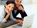 Joyful young couple using laptop while lying  | BahVideo.com