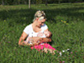Mother cradling baby on meadow | BahVideo.com