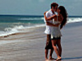 Happy couple kiss with ocean water at their feet | BahVideo.com